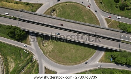 Overhead shot of a complex road junction surrounded by lush greenery and urban infrastructure