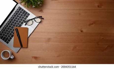 Overhead shot computer laptop, notebook and coffee cup on wooden desk. - Shutterstock ID 2004351164