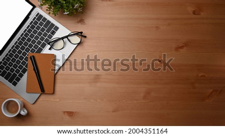 Overhead shot computer laptop, notebook and coffee cup on wooden desk.