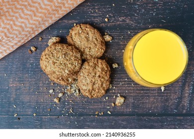 Overhead Shot Of Delicious Oatmeal Cookies Baked In The Oven With A Glass Of Orange Juice On A Dark Wood Background