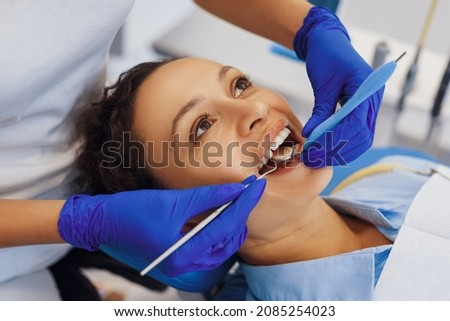 Overhead shot of dental doctor in latex gloves treating woman teeth in chair and using medical tools