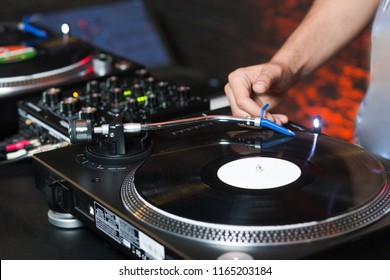 Overhead Shot Of Dj Controling Red Party Dj Audio Equipment.Turntable Top View High Quality Mixing Controller Disc Jockey In Night Club And Notebook .Pro Audio Equipment On Stage In Nightclub.