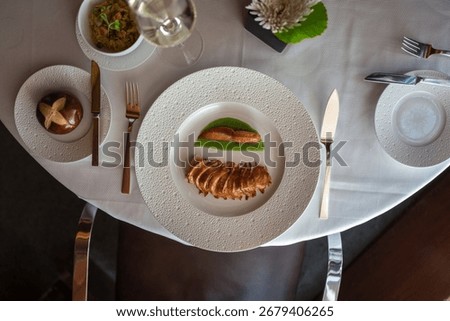 An overhead shot of an elegant table setting with a plated lobster dish and wine glass at a fine dining restaurant.