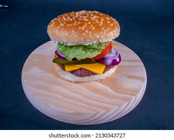 Overhead Shot Of An Exquisite And Delicious Cheeseburger On A Full Wooden Plate