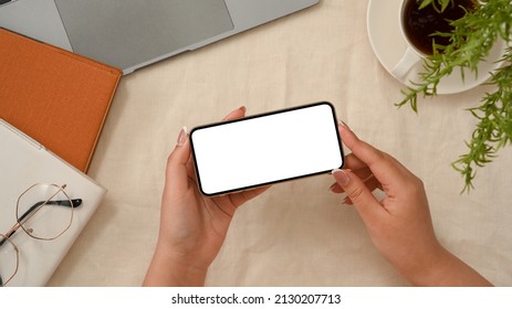 Overhead Shot, Female Hands Holding Mobile Phone Over Minimal Workspace. Watching Video, Playing Game, Looking Something On Online.