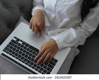 Overhead Shot Of Female Hands Typing On Laptop Keyboard On Her Lap While Sitting On Sofa 