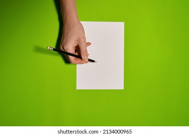 Overhead Shot Of Female Hands Writing With Pen Over Empty White Sheet Of Paper On Green Background