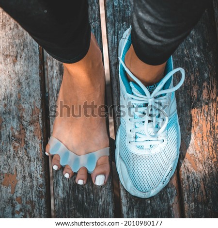 An overhead shot of a female wearing a blue sneaker on one foot and toe separators on the other