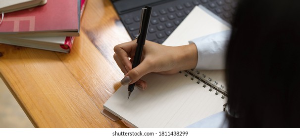 Overhead Shot Of Female Writing On Blank Notebook With Supplies On Wooden Table 