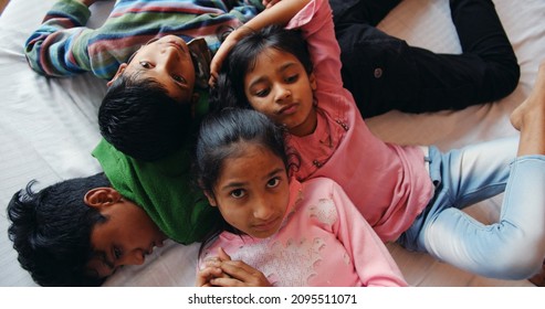 An Overhead Shot Of Four South Asian Kids Lying In The Bed