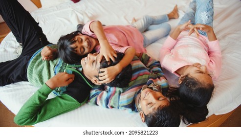 An Overhead Shot Of Four South Asian Kids Lying In The Bed