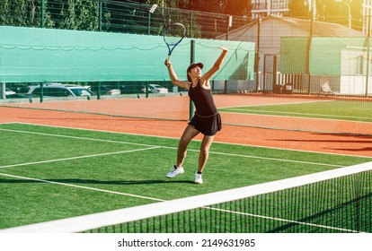 Overhead Shot From A Girl Practicing On A Brand New Outdoor Tennis Court. Vibrant Green And Brown With Clear White Lines. Putting In Her Weight. Sunlit In The Evening.