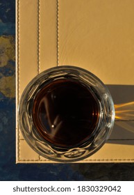 An Overhead Shot Of A Glass Of Cola On The Edge Of Table Mat On A Glass Table In The Sun