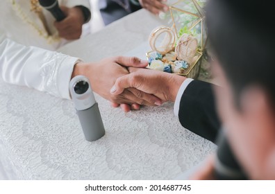 An Overhead Shot Of The Groom And Bride Holding Hands During An Indonesian Wedding Ceremony