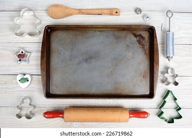 Overhead Shot Of A Group Of Items For Baking Christmas Cookies Surrounding An Empty Cookie Sheet. Horizontal Format On A  Rustic Wood Kitchen Table. 