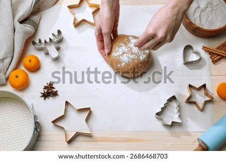 Overhead shot of hands adding flour to a ball of gingerbread dough, ready for holiday cookie making.