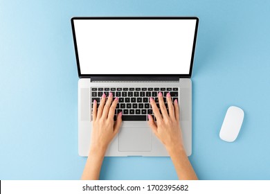 Overhead Shot Of Woman’s Hands Using Laptop With Blank Display On Blue Background. Modern Workspace Concept. Flat Lay