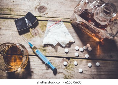Overhead shot of hard drugs and alcohol on wooden table. Addiction concept