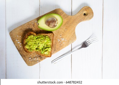 Overhead Shot With Healthy Avocado Toast On Whole Wheat On Bread On Board Over White Wooden Background