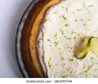 Overhead Shot Of A Key Lime Pie With Whipped Cream Topping. A Sliver Of The Filling Can Be Seen Between The Crust And The Cream