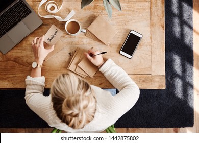 Overhead Shot Looking Down On Woman Writing In Generic Thank You Card