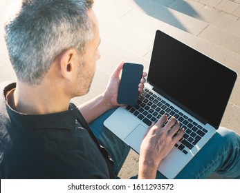 Overhead Shot Of Man Using Laptop And Phone Outside At Sunset