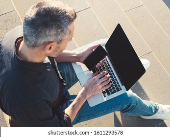 Overhead Shot Of Man Using Laptop And Phone Outside At Sunset