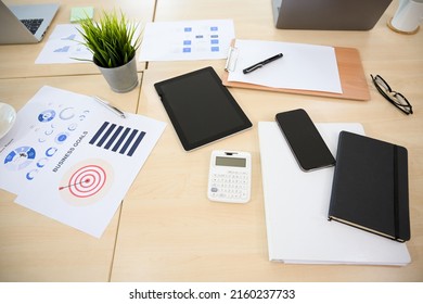 Overhead Shot, Messy Office Desk With Business Report Paperwork, Tablet, Calculator And Supplies.