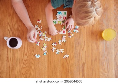 Overhead Shot Of Mother And Daughter Sitting At Table At Home Doing Jigsaw Puzzle Together