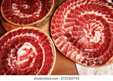 An overhead shot of multiple circular platters filled with premium Iberian cured ham slices for a large event.