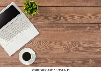 Overhead Shot Of Office Table With White Laptop, Coffee Cup And Green Plant