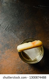 Overhead Shot Of An Old Fashioned Cocktail With Orange Zest Garnish On Rusty Background.