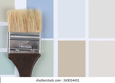 Overhead shot of  a paint brush with a brown handle laying on a sheet of color samples. Horizontal format with copy space.