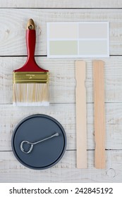 Overhead Shot Of  A Paint Can Lid, Opener, Color Samples, Stir Sticks And Paint Brush On A Rustic Wooden Surface. Vertical Format With Copy Space.