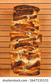 An overhead shot shows a pull-apart bread loaf with a poppy seed, lemon, and cheese filling resting on a cooling rack