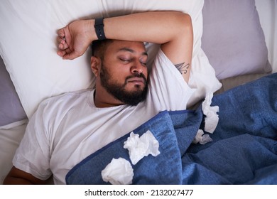 An Overhead Shot Of A Sick Man Sleeping In Bed Surrounded By Tissues. High Quality Photo