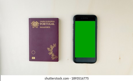 An overhead shot of a smartphone with a green screen and a Portuguese passport