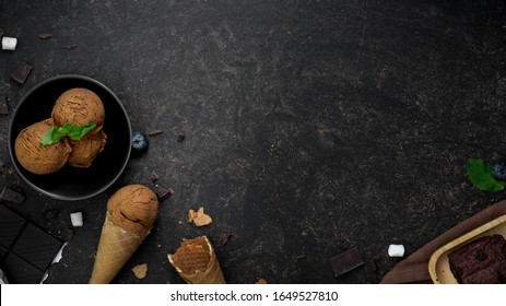 Overhead Shot Of Summer Dessert With Chocolate Flavour Ice-cream, Cones, Brownie, And Copy Space On Dark Table Background