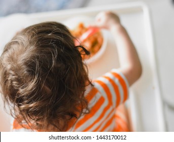 Overhead Shot Of A Toddler Eating In A Baby High Chair