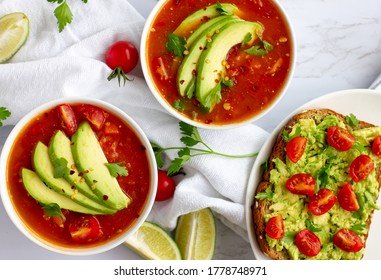 Overhead Shot Of Two Bowls Of Tomato Soup With Avocado Toast On A Folded White Napkin On A Marble Counter Top