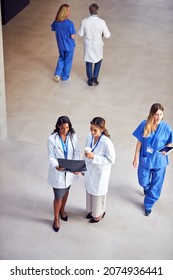 Overhead Shot Of Two Female Medical Staff In White Coats Discussing Patient Scan In Busy Hospital