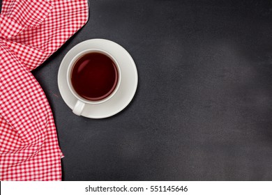 Overhead Shot Of White Cup And Red And White Tea Towel On A Blackboard Surface