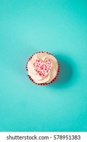 Overhead Shot Of White Frosting Cupcake Topped With A Candy Heart.