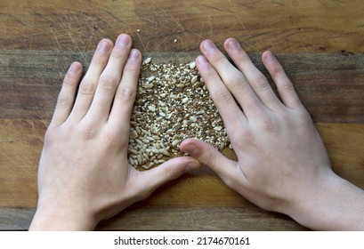 Overhead Shot Of White Man's Hands Arranging Sunflower Seeds And Almonds On A Rustic Wooden Table
