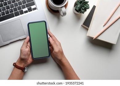 Overhead Shot Of Woman Hands Holding Mock Up Mobile Phone With Blank Screen At Her Office Desk.