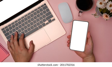 Overhead Shot Woman Holding Mobile Phone And Typing On Laptop Computer.