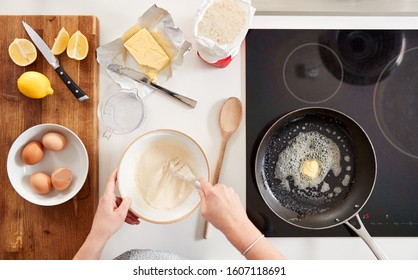 Overhead Shot Of Woman In Kitchen Mixing Ingredients For Pancakes Or Crepes For Pancake Day