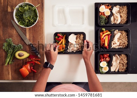 Overhead Shot Of Woman Preparing Batch Of Healthy Meals At Home In Kitchen