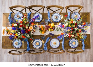 An Overhead Shot Of A Wooden Table And Chairs Decorated With Flowers, Candles, Bowls Of Fruit, Etc