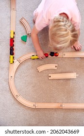 Overhead Shot Of Young Girl At Home Playing With Wooden Train Set Toy